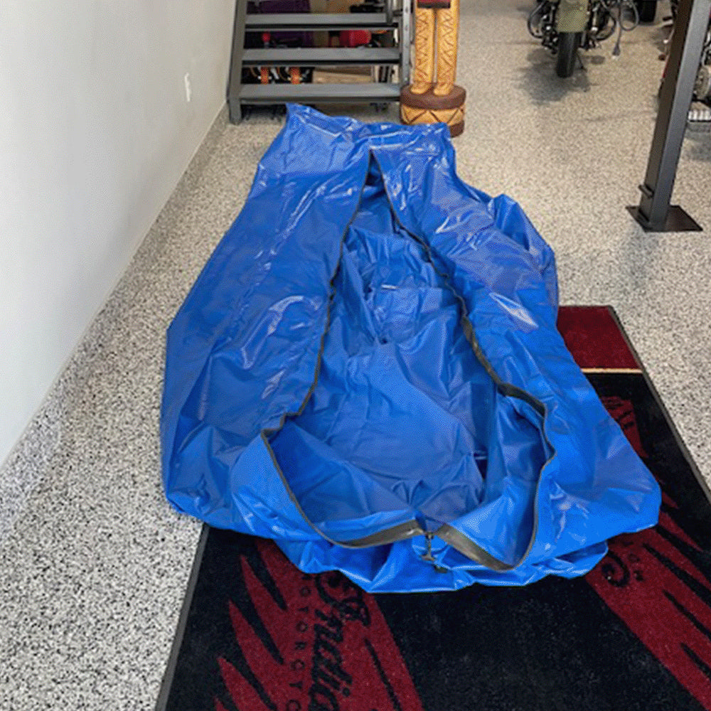 Unrolled FloodVault Moto envelope on a garage floor, ready for the motorcycle.